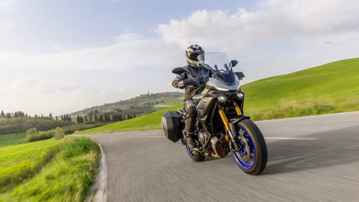 Yamaha Tracer 7 GT med vožnjo v ovinku, zmogljiv touring motocikel z zaščito pred vetrom in stranskimi kovčki