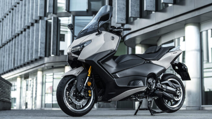 Yamaha TMAX Tech MAX 2026 parkiran pred arhitekturo, 7-palčni TFT, električni vizir, premium izvedba
